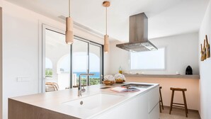 Una cocina moderna con una isla grande, electrodomésticos de acero inoxidable e iluminación colgante.