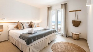 Un dormitorio con cama, mesitas de noche, una ventana con cortinas y vistas al exterior, además de una cesta colgante.