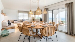 Un comedor con una mesa redonda, sillas de mimbre y lámparas colgantes de ratán.