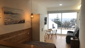 Un salon moderne avec un banc en bois, une table à manger avec des chaises, un canapé et une grande fenêtre donnant sur l’extérieur.