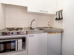 Una cocina compacta con estufa, lavabo y horno.