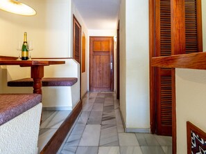 A hallway with a marble floor, wooden benches, and a door at the end.