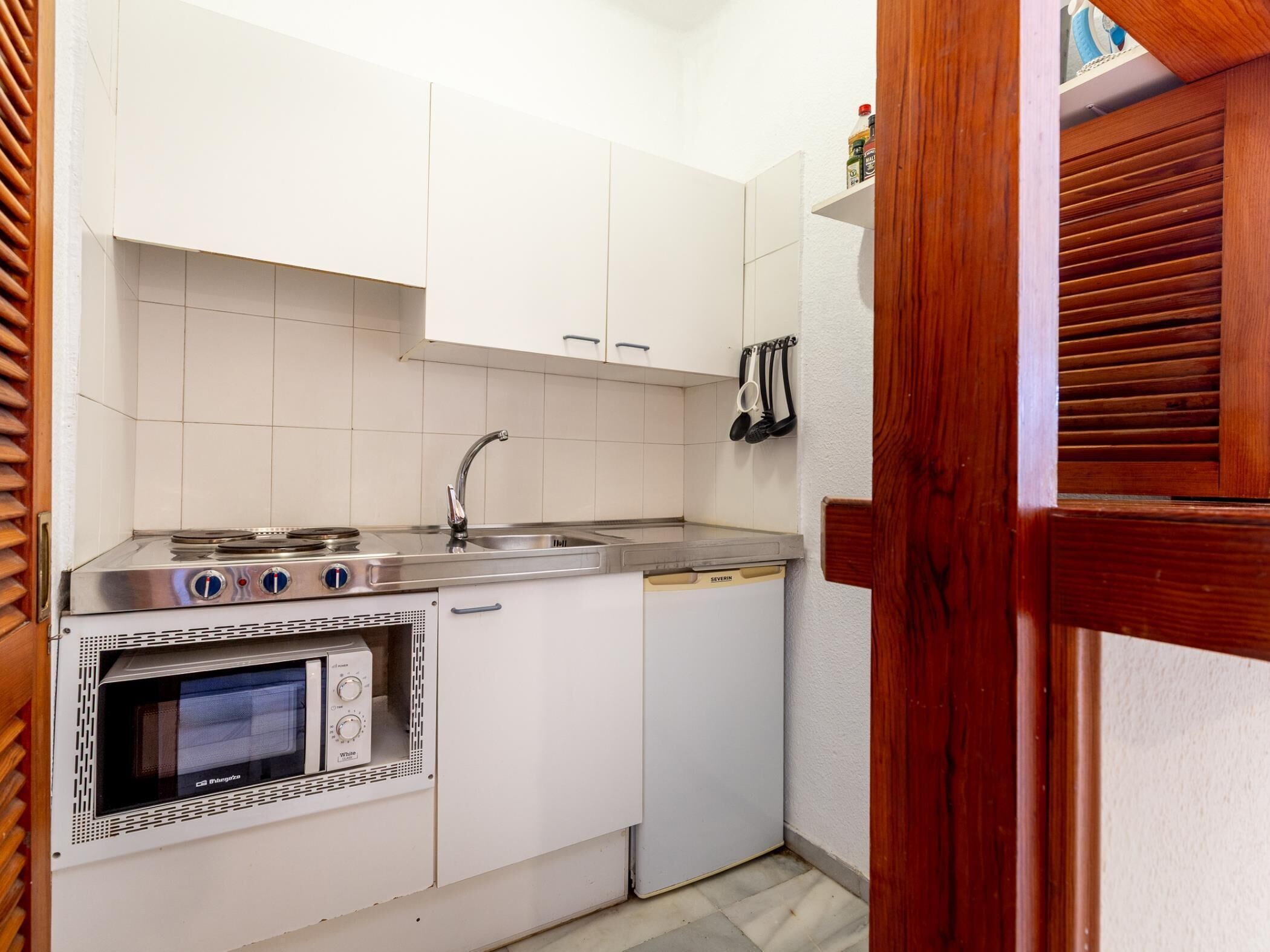 A compact kitchen with a built-in oven, a stovetop, and a sink.