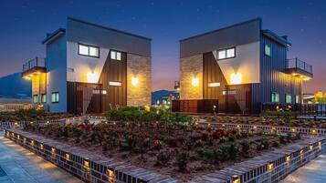 A modern building with two symmetrical sections, each with a balcony and a flat roof.