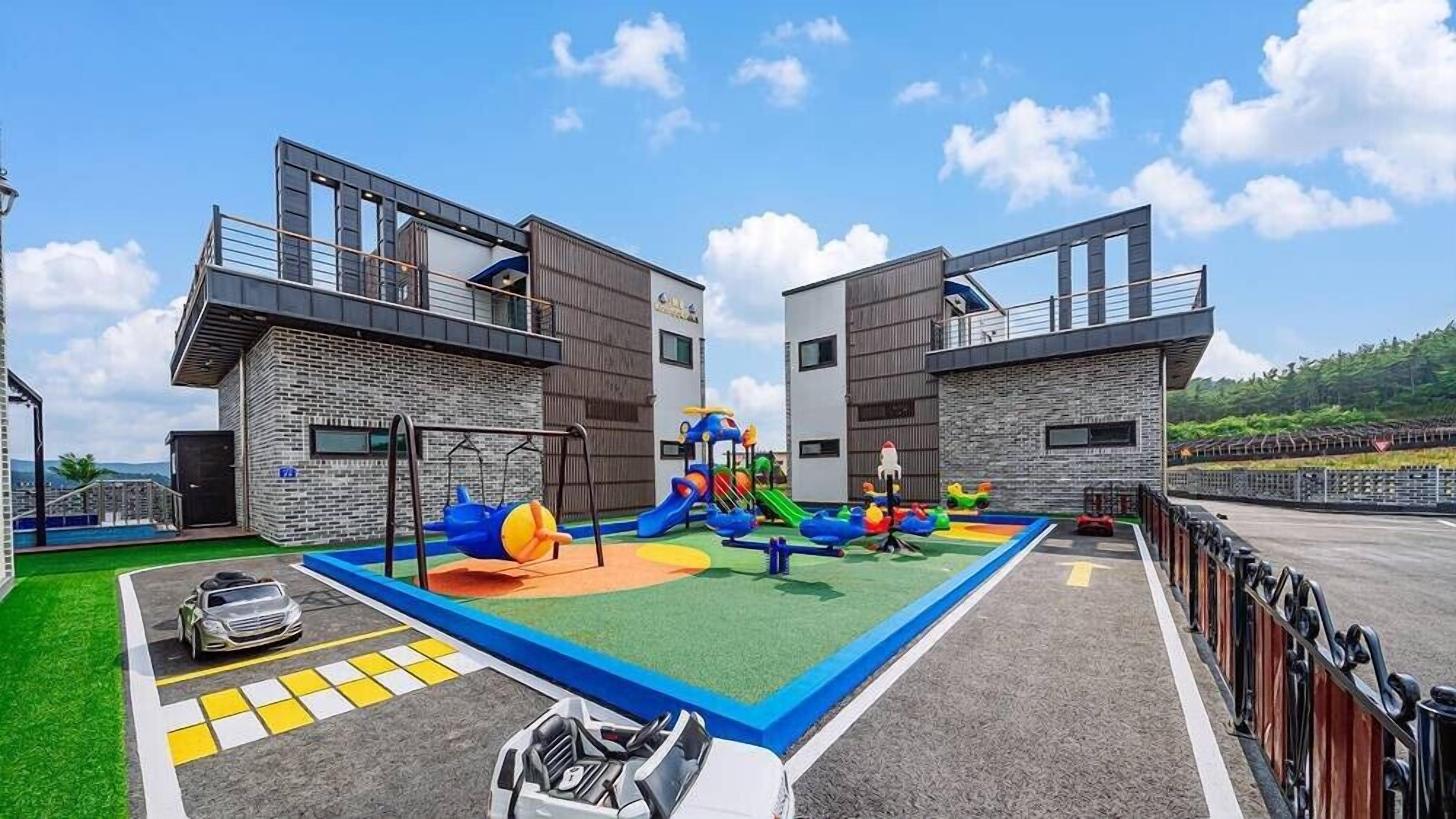 Un parque infantil con toboganes y estructuras de escalada, rodeado de edificios modernos con balcones.