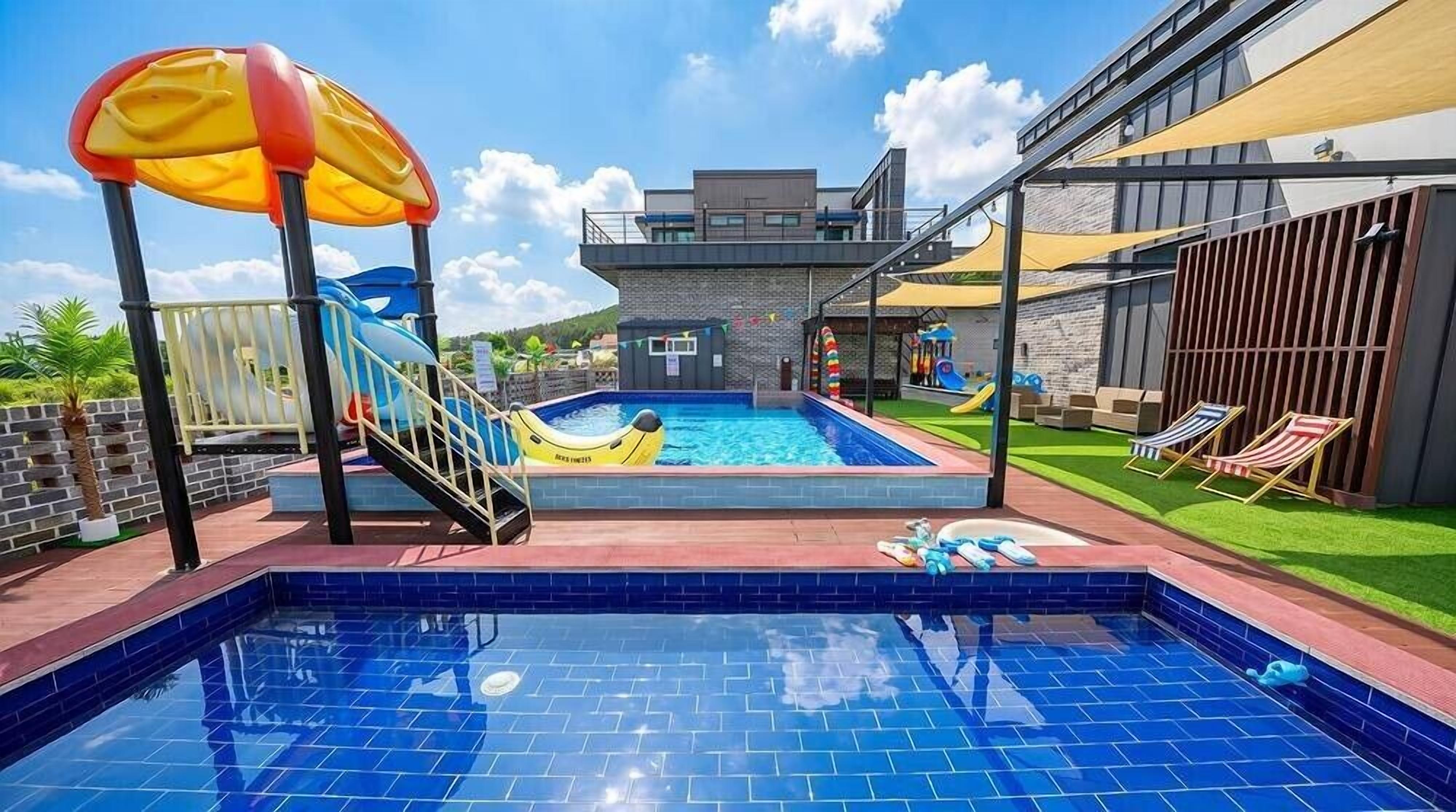 A swimming pool with a slide and a children's play area.