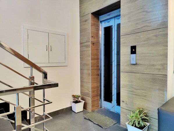 A modern interior with a staircase, a wooden wall, and an elevator. - Hotel Park Hills (Mohali)