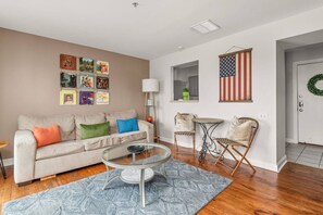 A living room with a sofa, coffee table, and wall decorations including a framed American flag and movie posters.