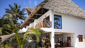 A two-story resort with a pool, palm trees, and a thatched roof. - Alladin Beach Hotel and SPA Zanzibar (Matemwe)