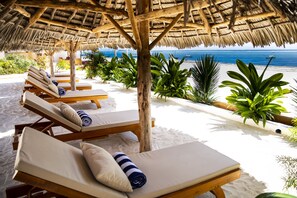A beachside lounge area with wooden loungers and a thatched roof, overlooking the ocean. - Alladin Beach Hotel and SPA Zanzibar (Matemwe)