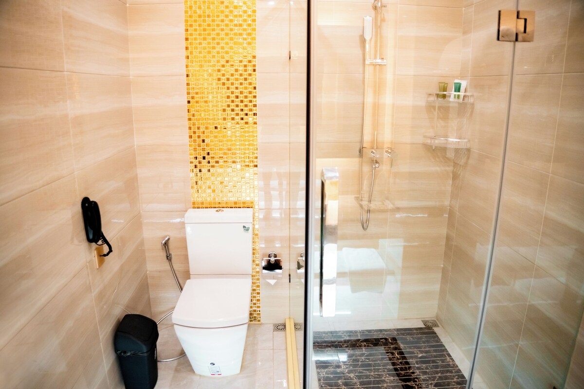 Een moderne badkamer met een douchecabine van glas, een toilet en een prullenbak.