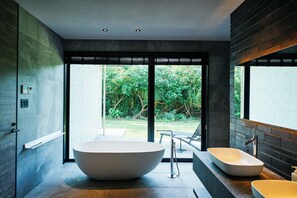 A modern bathroom with a large freestanding bathtub, a smaller sink, and a glass shower enclosure. - Villa El Cielo Ishigaki (Ishigaki)