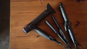 A wooden table with four hair styling tools laid out.