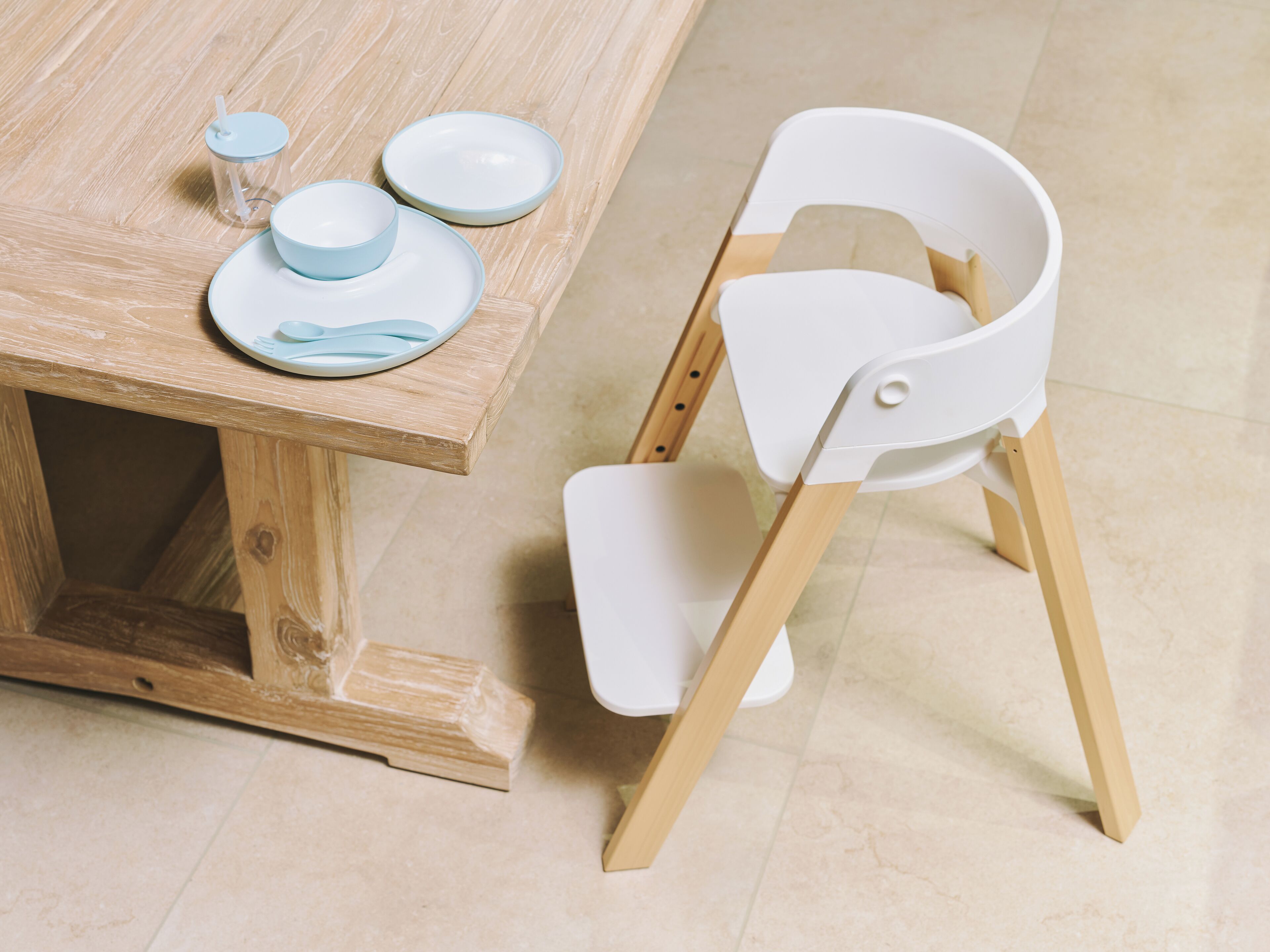 A wooden table with a white chair and a small table lamp.