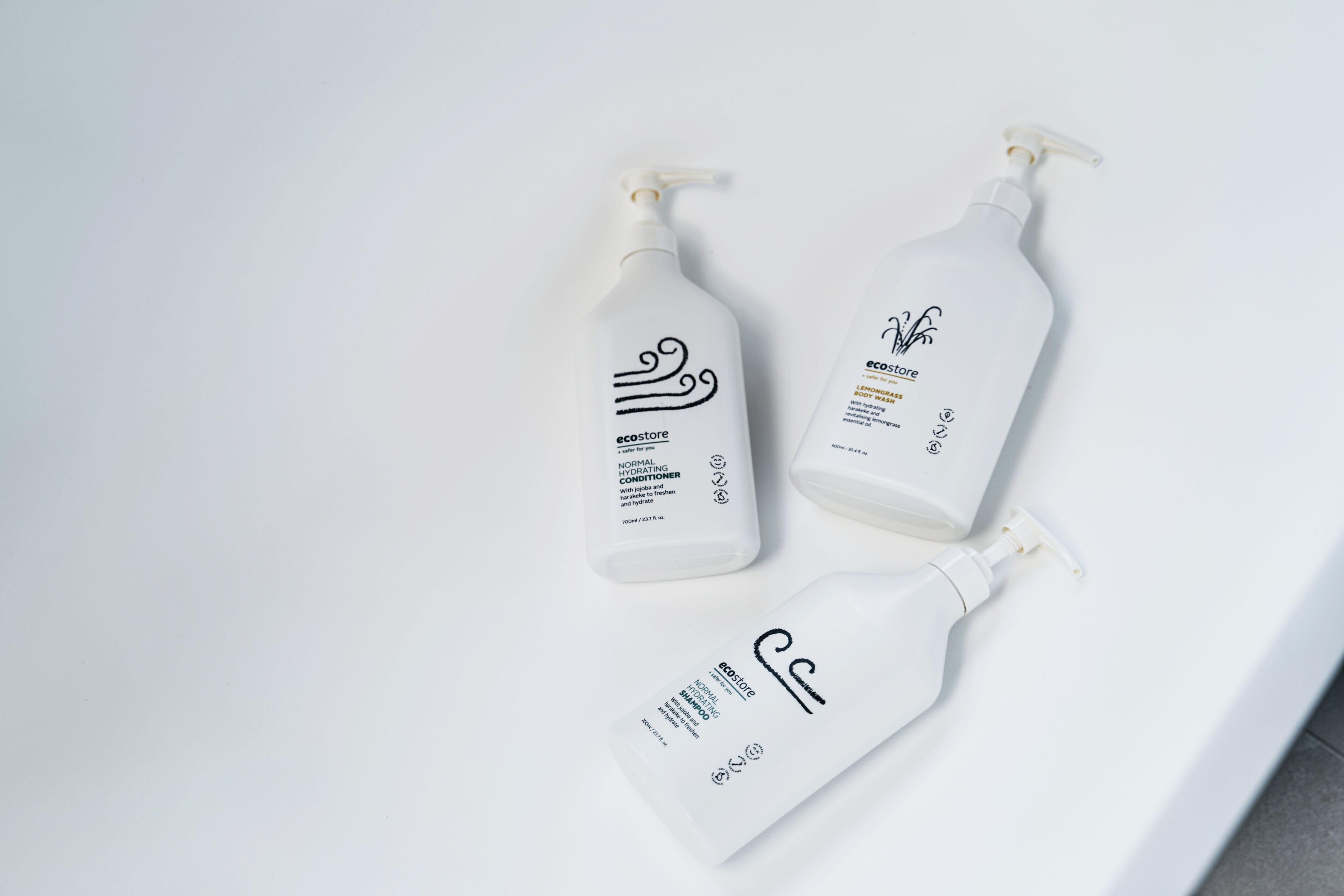 Tres botellas de productos para el cuidado de la piel sobre una superficie blanca.