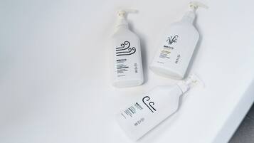 Tres botellas de productos para el cuidado de la piel sobre una superficie blanca.