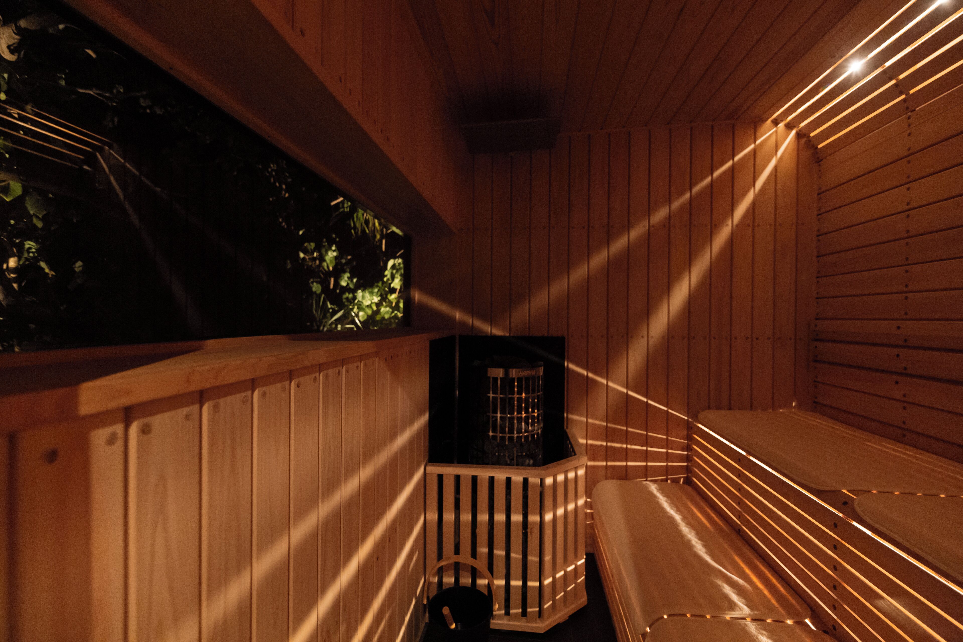 Una sauna in legno con panche e un piccolo ambiente chiuso con uno scaldabagno.