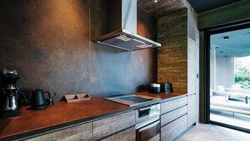 A modern kitchen with a wooden countertop, built-in oven, and a large window providing a view of the outdoors.