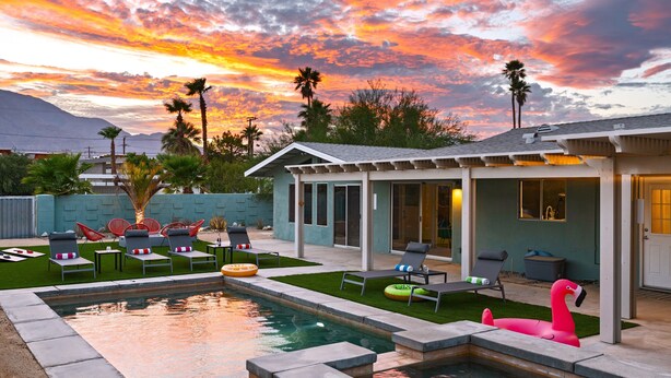 Un jardin avec une piscine, des chaises longues et un flotteur en forme de flamant rose.