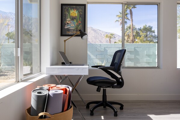 Une pièce comprenant un bureau, une chaise et de grandes fenêtres donnant sur une montagne.