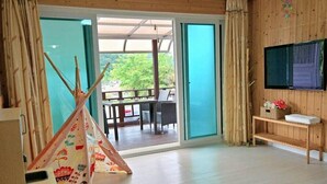Ein Zimmer mit einer Schiebetür zum Außenbereich, einem Holz-Fernsehmöbel und einem bunten Teepee.