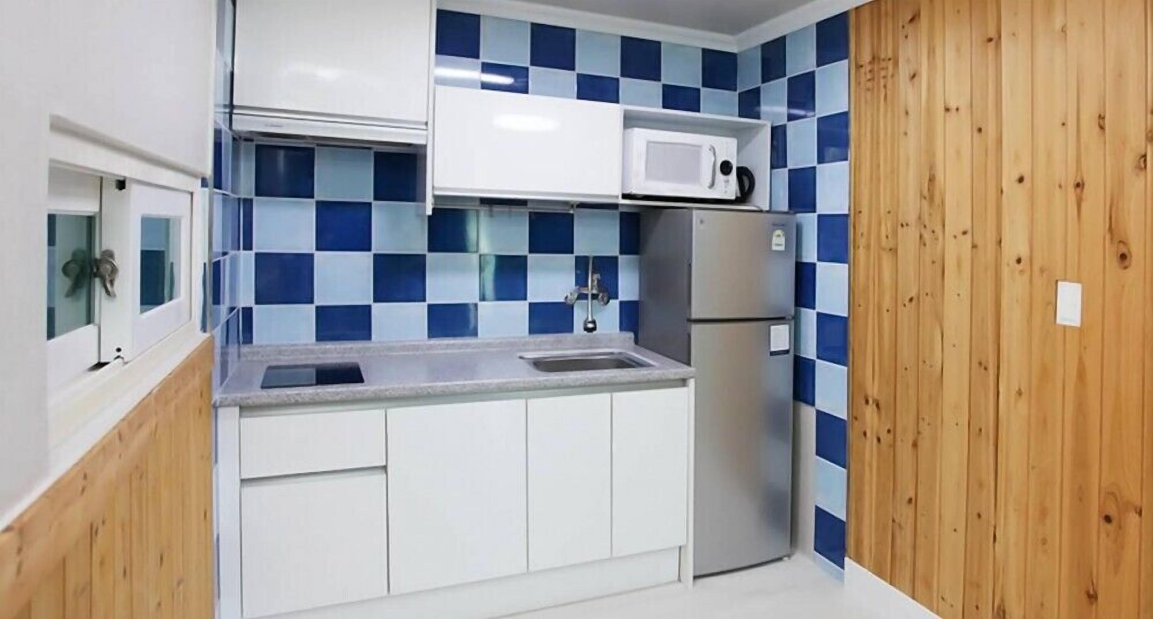 Uma cozinha compacta com micro-ondas, geladeira e pia.