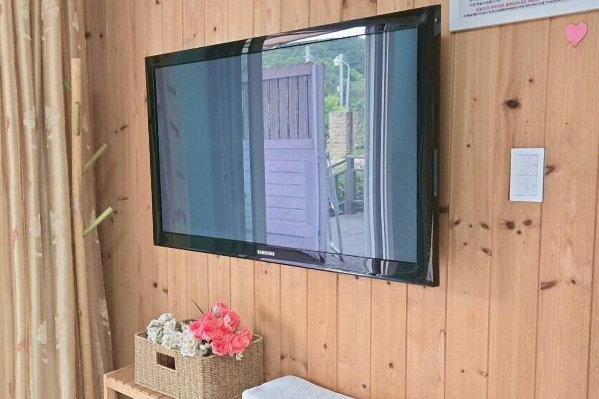 A television mounted on a wooden wall with a basket of flowers below it.