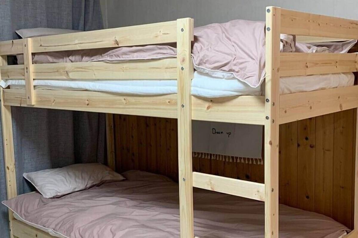A bunk bed with two levels, each with a pillow and a blanket.
