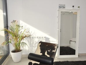 Relax in a serene space with a large window, potted plant, and stylish bench.