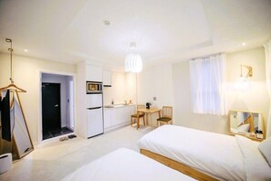 Une chambre d’hôtel moderne dotée d’une kitchenette, de deux lits, d’un coin repas et d’une salle de bain.