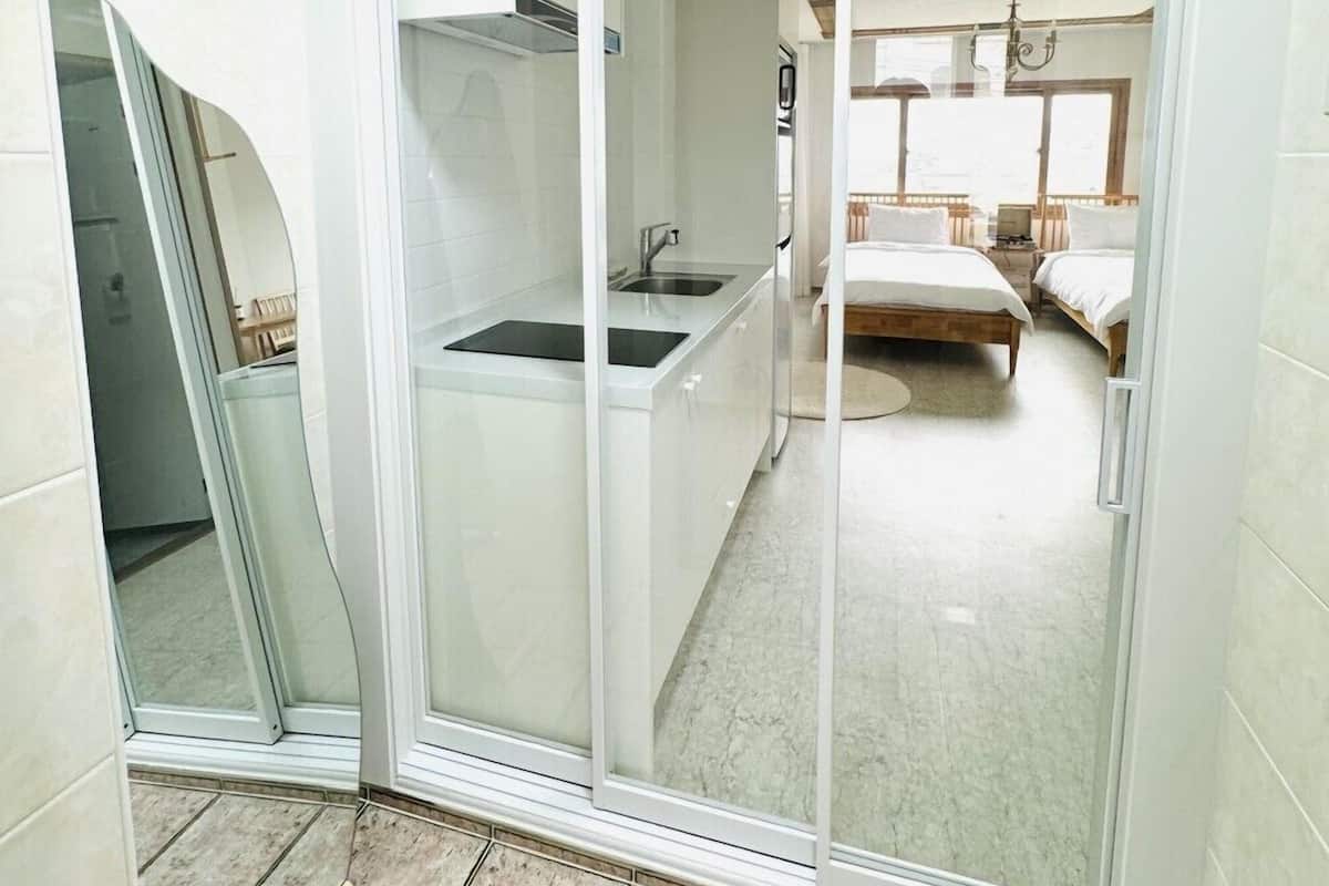 Une chambre d’hôtel moderne dotée d’une porte-fenêtre coulissante donnant sur un coin cuisine.