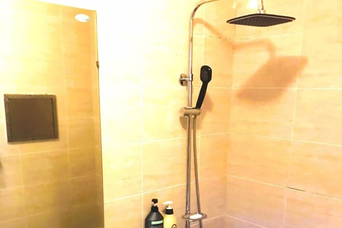 Une douche équipée d’un pommeau de douche à main et d’un panneau de commande fixé au mur.