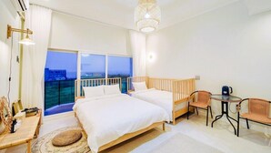 Une chambre d’hôtel avec deux lits, un balcon, un coin repas et une vue sur le paysage urbain.