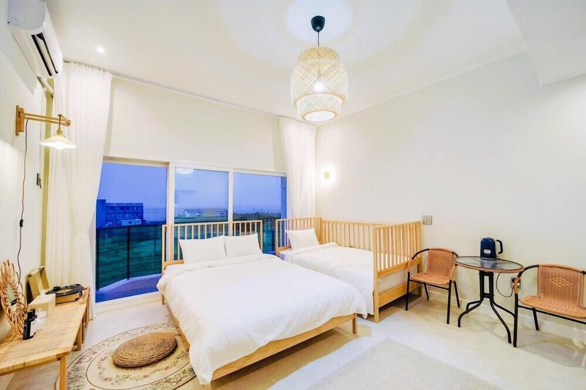 Une chambre d’hôtel avec deux lits, un balcon, un coin repas et une vue sur le paysage urbain.