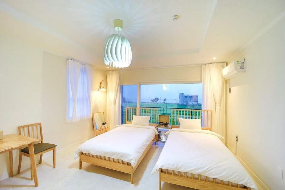 Une chambre d’hôtel avec deux lits, une table à manger et une vue sur un immeuble par la fenêtre.