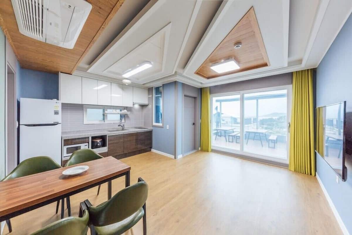 Una cocina moderna con armarios blancos, una mesa de comedor de madera y un amplio ventanal con vistas.