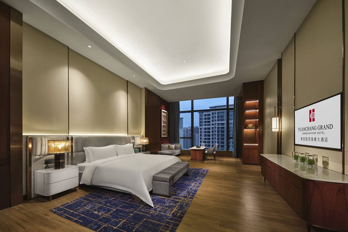 Habitación de hotel moderna con una cama grande, un escritorio y vistas a la ciudad.