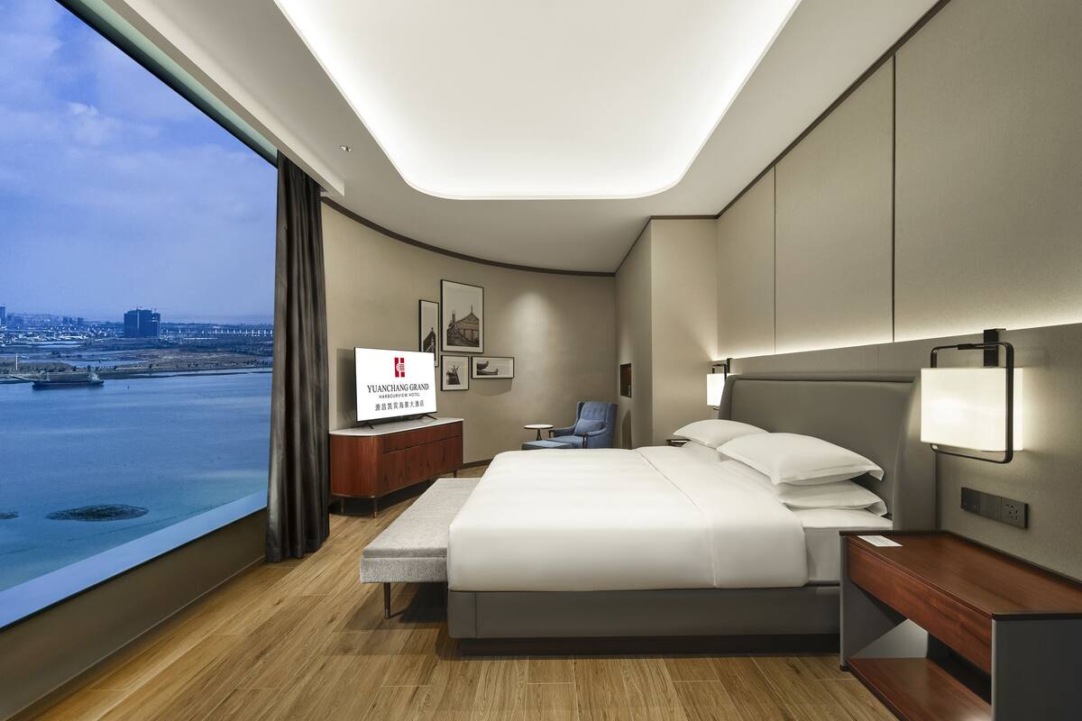 Una habitación de hotel moderna con una cama grande, un escritorio, una silla y un televisor.