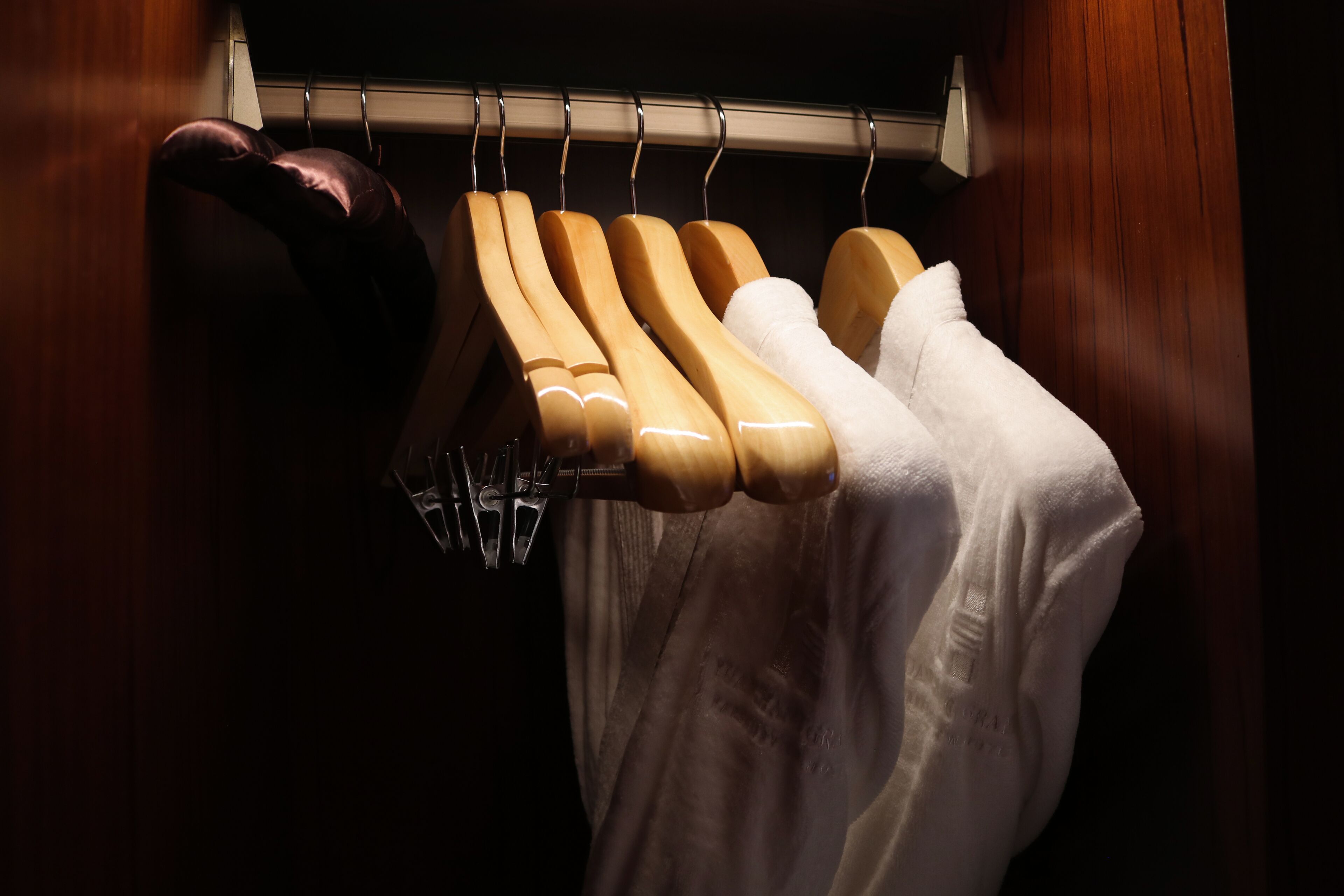 A wooden closet with a hanging rod and a folded towel.