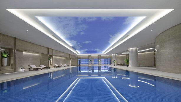 A modern indoor swimming pool with a skylight ceiling, lounge chairs, and a clean, minimalist design. - Yuanchang Grand Harbourview Hotel (Quanzhou)