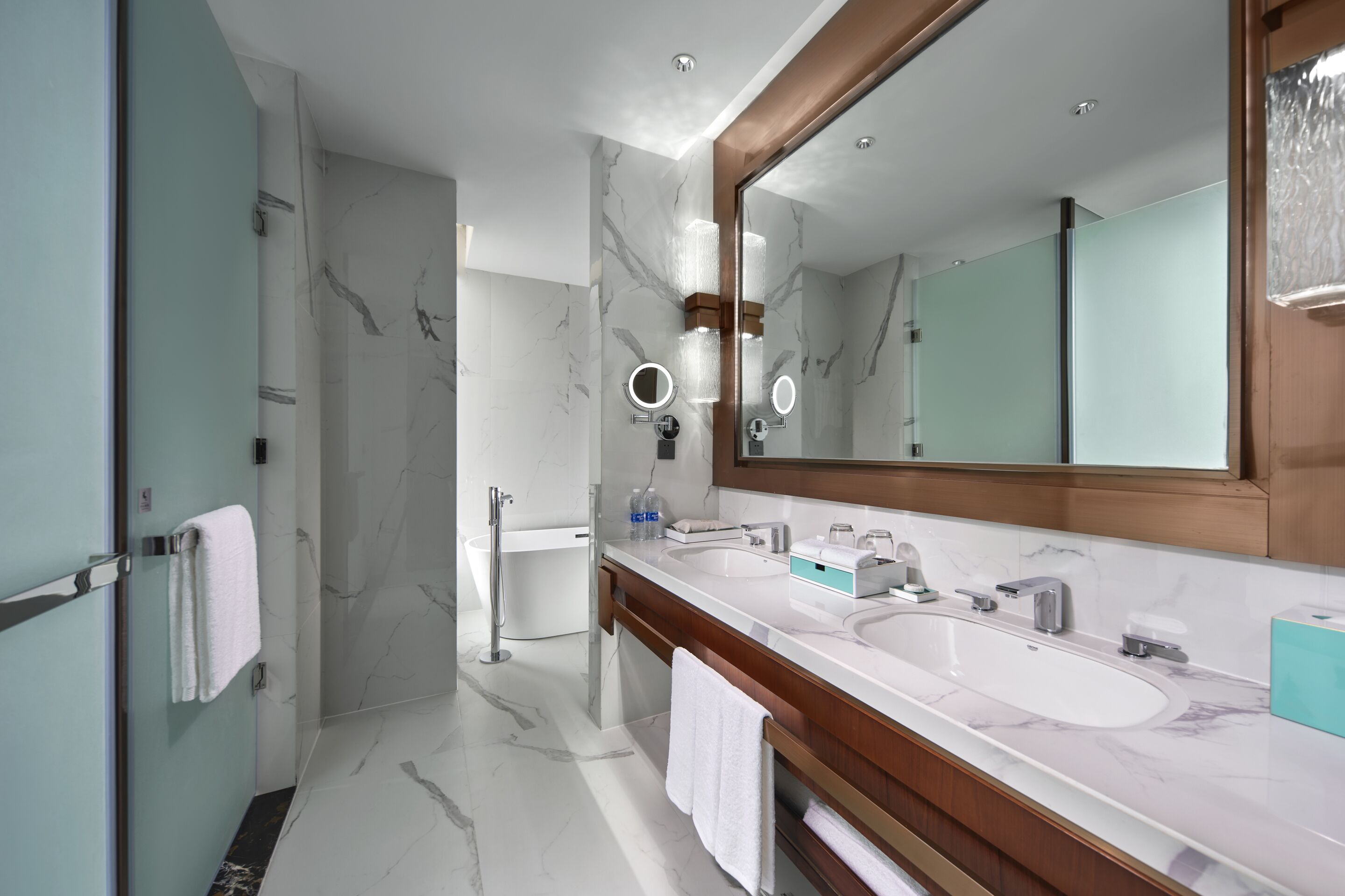Une salle de bain moderne avec deux lavabos, un grand miroir et un espace douche.