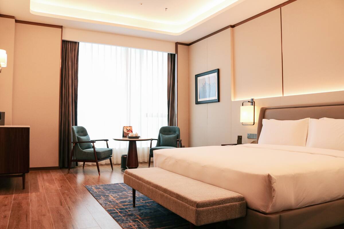 Habitación de hotel con una cama grande, dos sillas, una mesita y un banco.