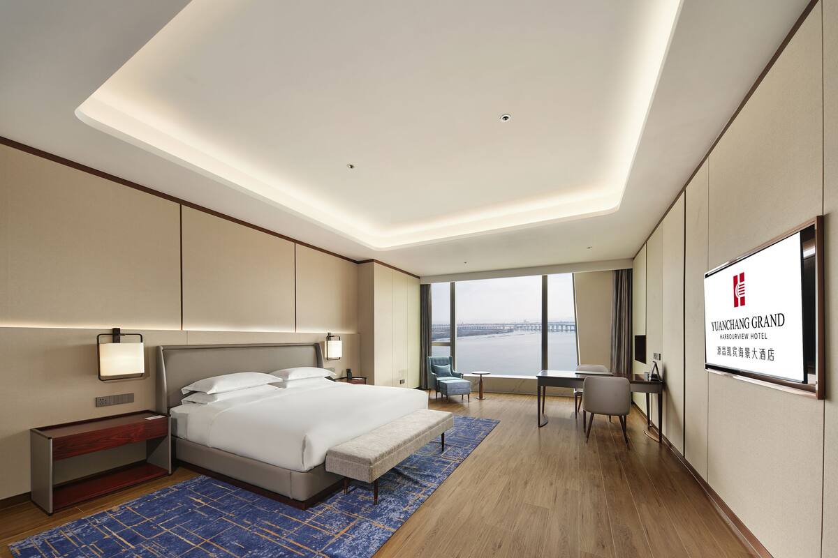 Una habitación de hotel moderna con una cama grande, un escritorio y vistas a una masa de agua.