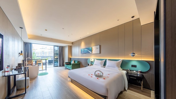 Habitación de hotel moderna con una cama grande, un escritorio, una silla y vistas a la ciudad.