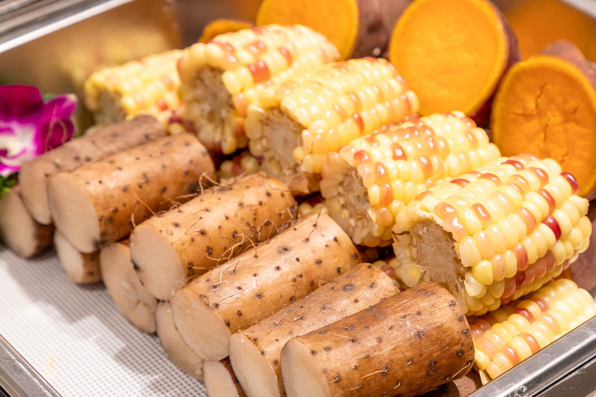 Ein Buffet mit geschnittenem Fleisch, Maiskolben und Orangenscheiben.
