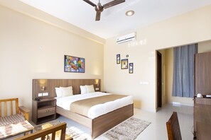 Una habitación de hotel moderna con una cama grande, un escritorio, una silla, un ventilador de techo y un equipo de aire acondicionado.
