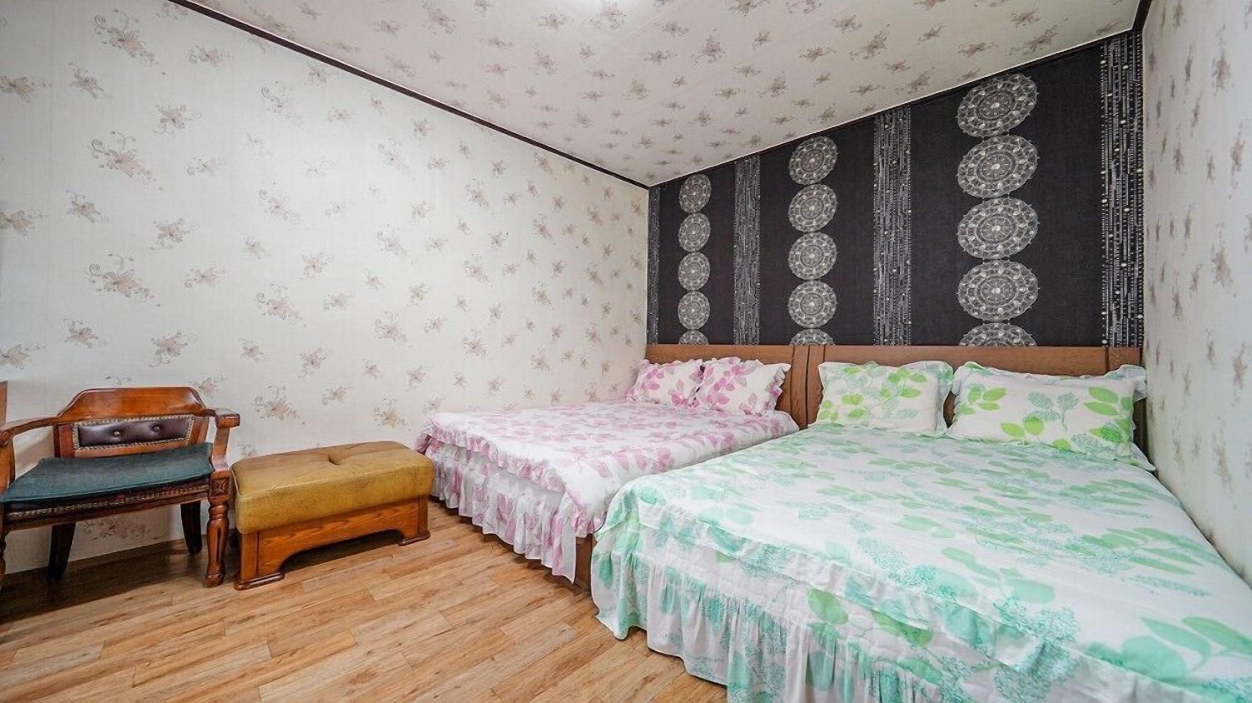 Ein Schlafzimmer mit zwei Einzelbetten, einem Holzstuhl und einer kleinen Bank.