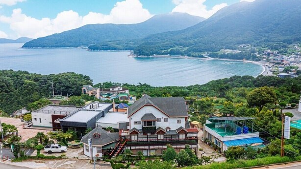 A coastal property with a large house, a swimming pool, and a view of the sea and mountains. - Mangyang Full House (Geoje)