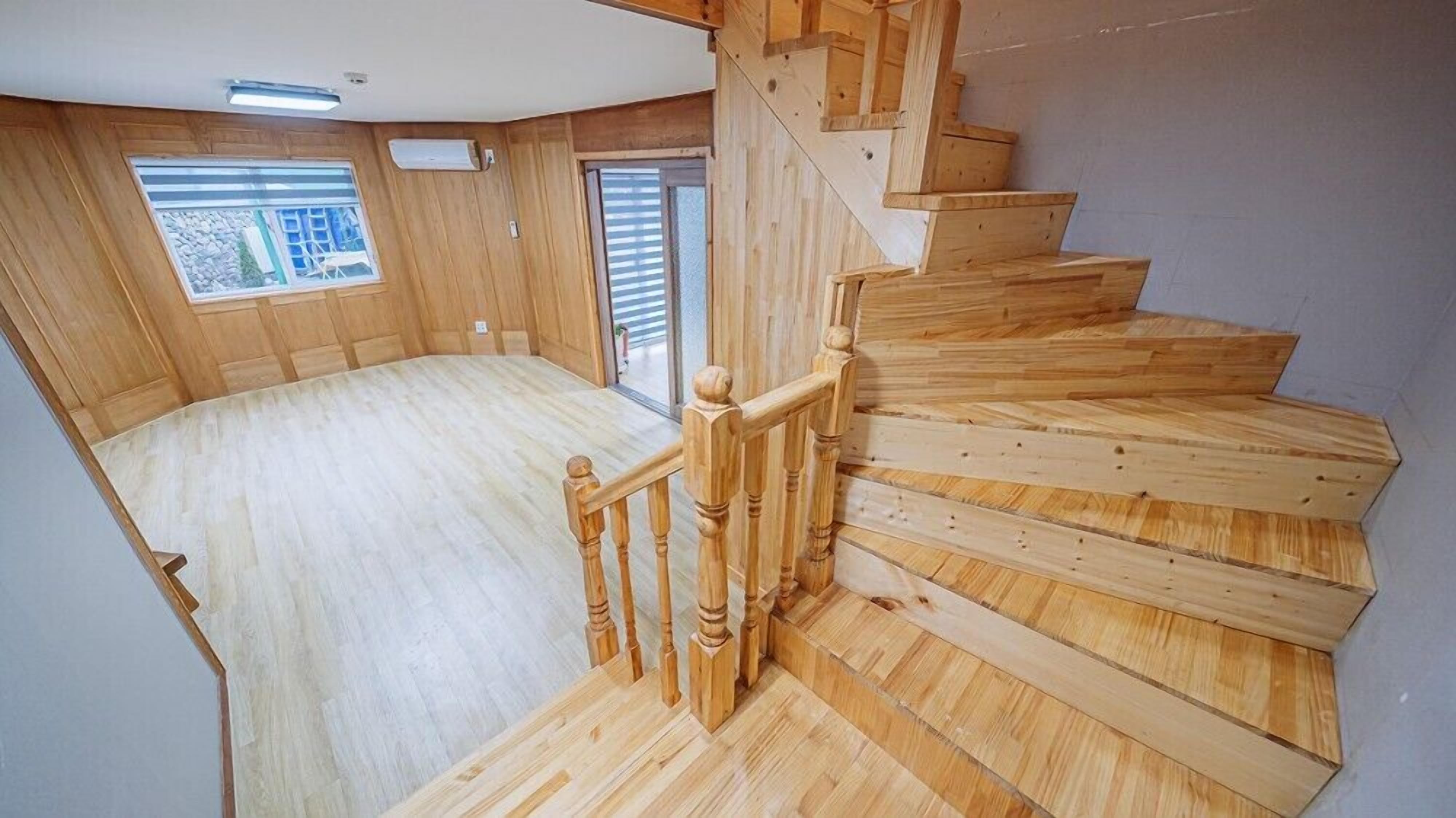 A wooden staircase leading to a room with a large window and a view of the outside.