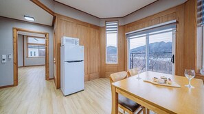A modern kitchen with wooden paneling, a white refrigerator, and a dining area with a table set for two. - count star night (Gapyeong)